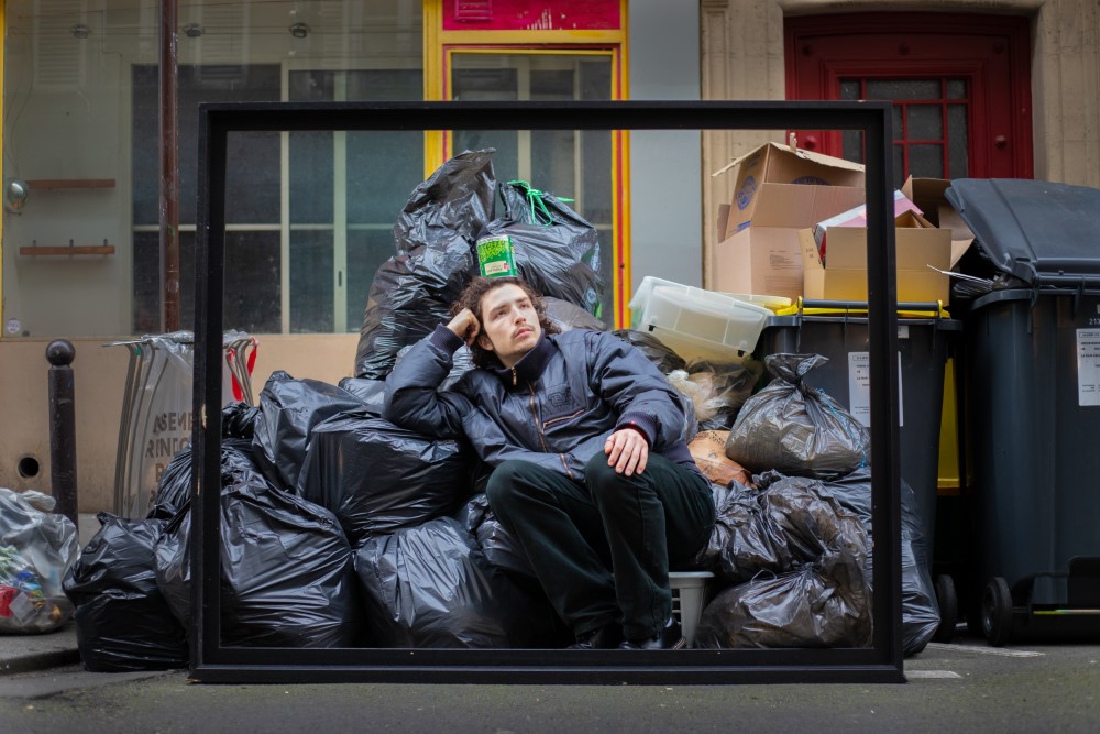 Un hombre sentado en la basura en las calles de Paris.